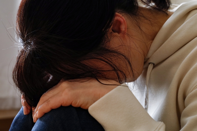 膝を抱えてうなだれる女性
