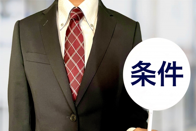『条件』の札を持つ男性