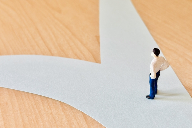 分かれ道の前に立つ男性